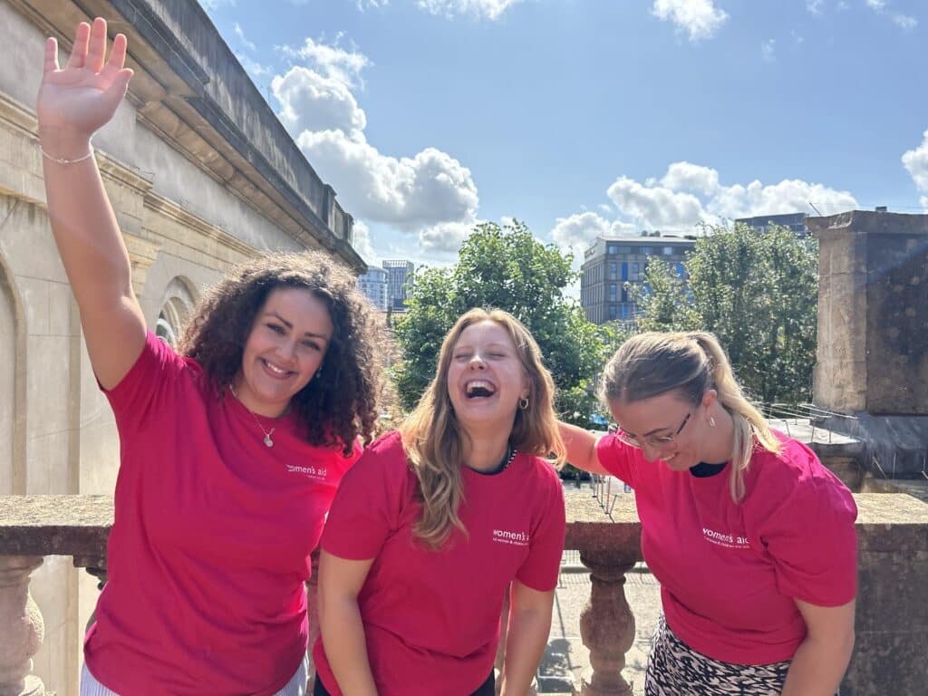Women smiling wearing Women's Aid t-shirts