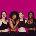 Group of women standing together smiling in front of plum background