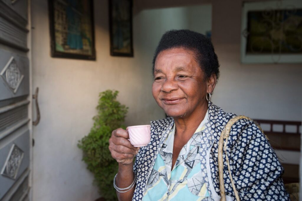 Woman standing smiling and holding a small mug