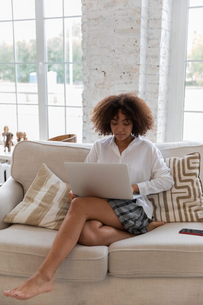 Woman sitting on couch looking at laptop